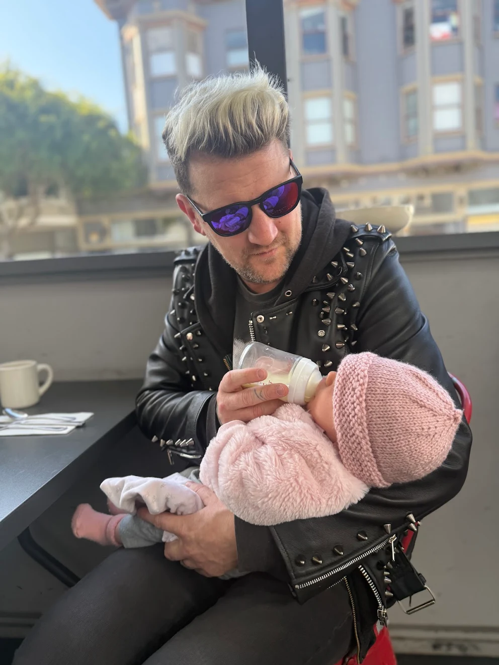 MAN IN STUDDED LEATHER JACKET HOLDING BABY
